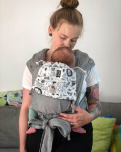 kvinna bär spädbarn i en grå knytsele från Limas