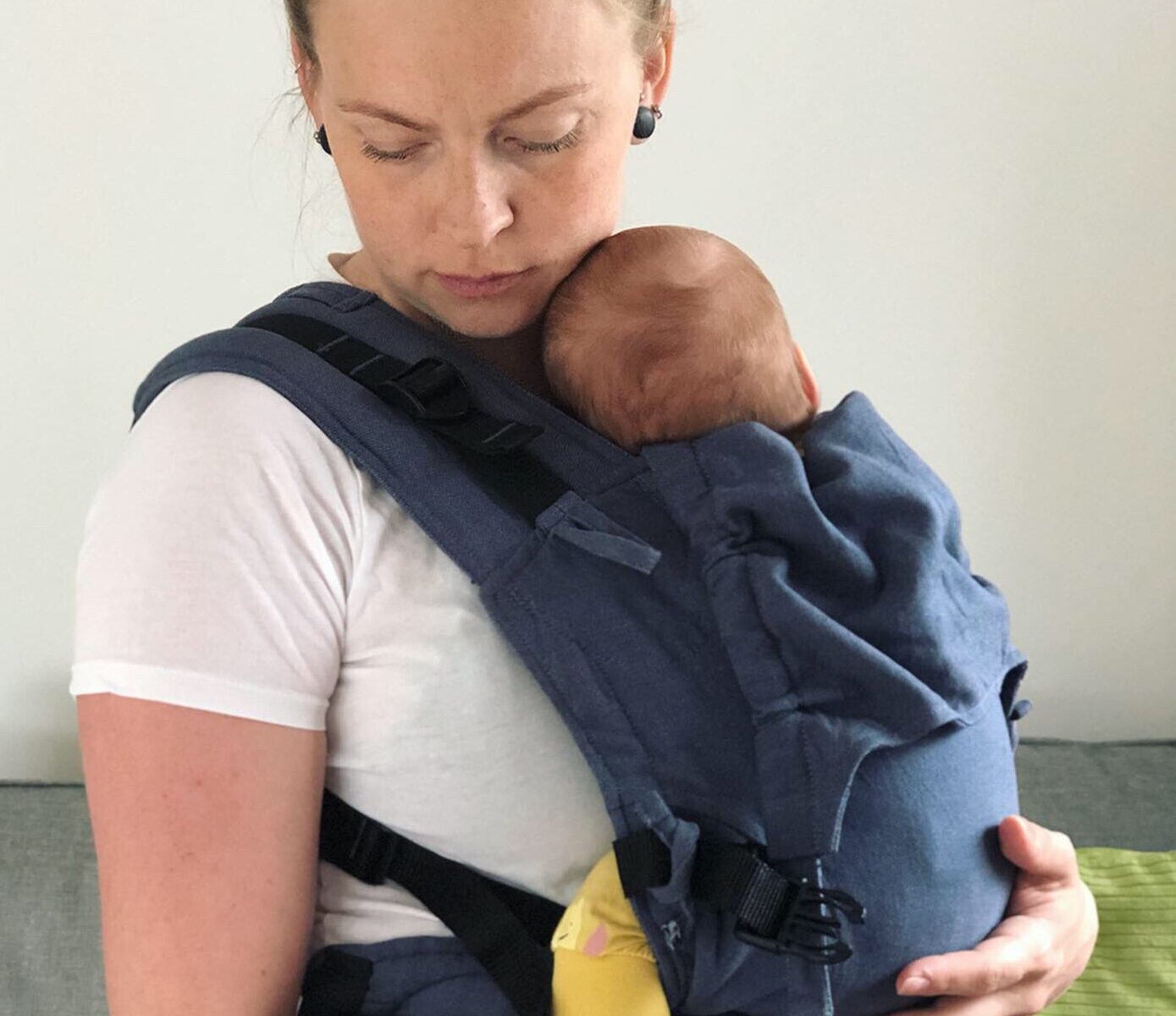 kvinna bär spädbarn i en blå sele av märke Fidella